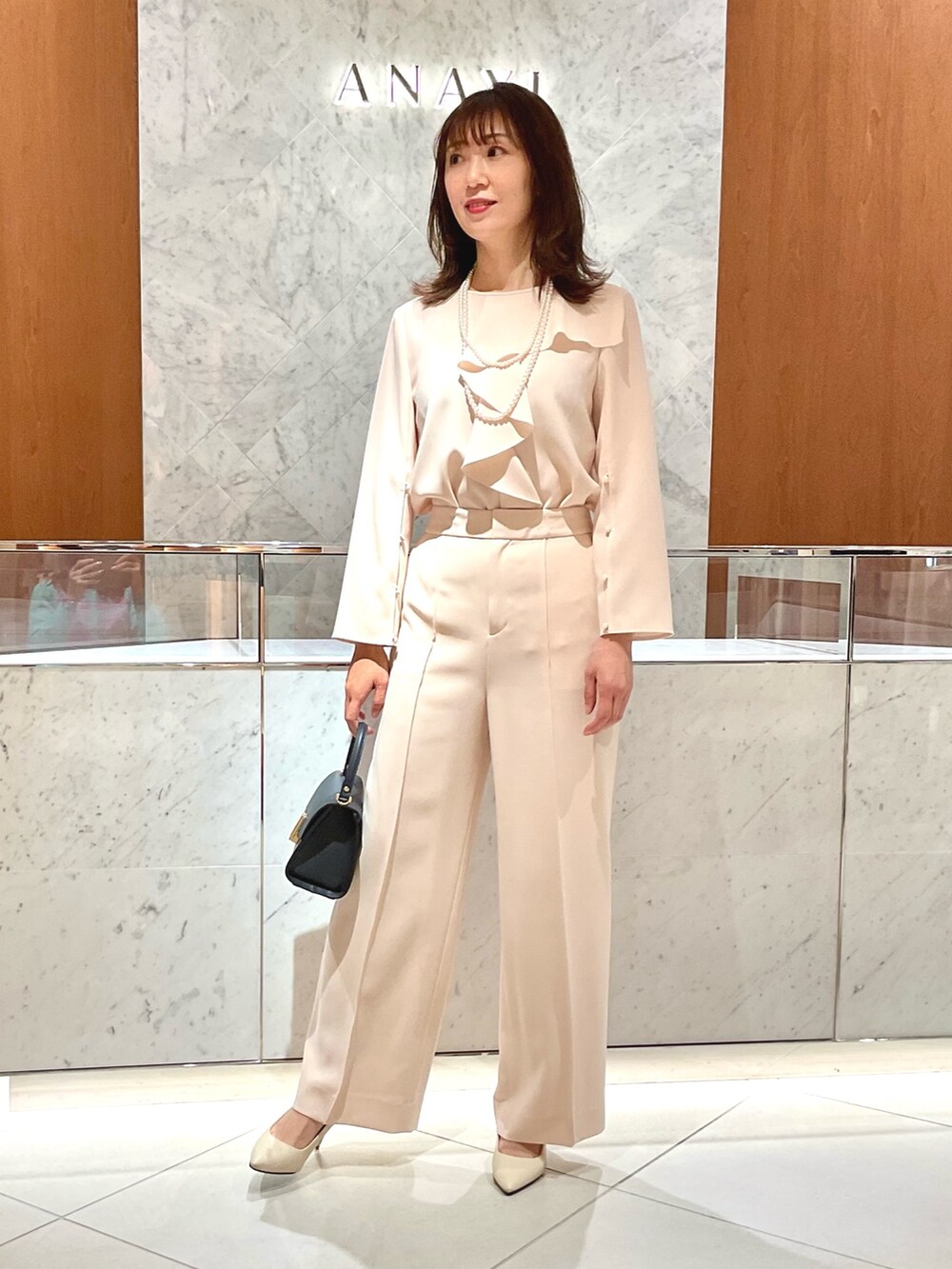 ベージュ系のシャツ/ブラウス、ベージュ系のその他パンツ、ブルー系のトートバッグを着用したレディースの冬コーディネートの2枚目の写真