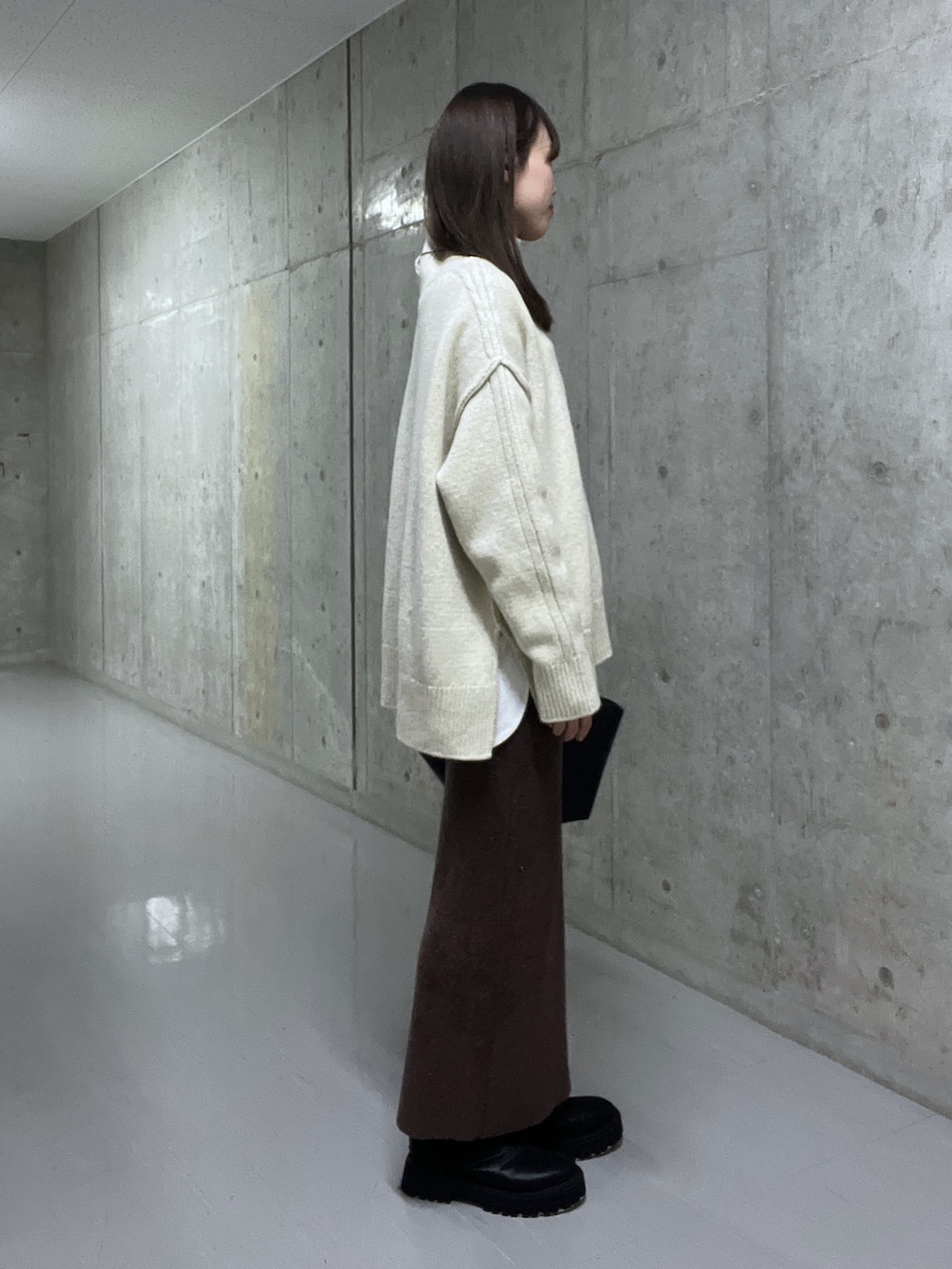 ホワイト系のニット/セーター、ブラウン系のスカート、ブラック系のブーツを着用したレディースの秋コーディネートの2枚目の写真