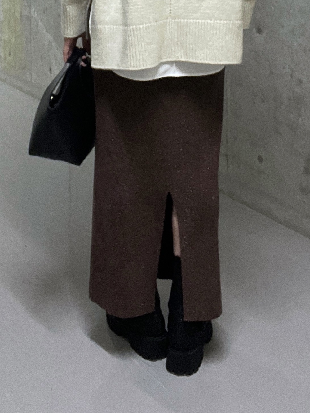 ホワイト系のニット/セーター、ブラウン系のスカート、ブラック系のブーツを着用したレディースの秋コーディネートの9枚目の写真