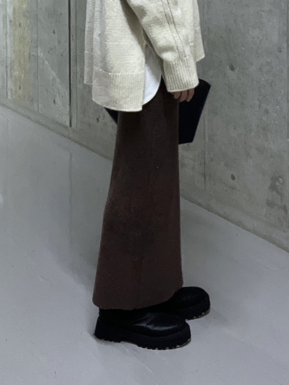 ホワイト系のニット/セーター、ブラウン系のスカート、ブラック系のブーツを着用したレディースの秋コーディネートの8枚目の写真