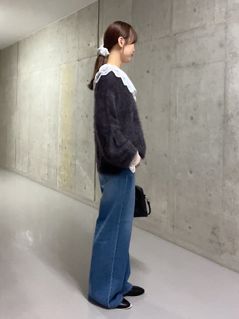 グレー系のニット/セーター、ホワイト系のシャツ/ブラウス、ブルー系のデニムパンツを着用したレディースの秋コーディネートの2枚目の写真