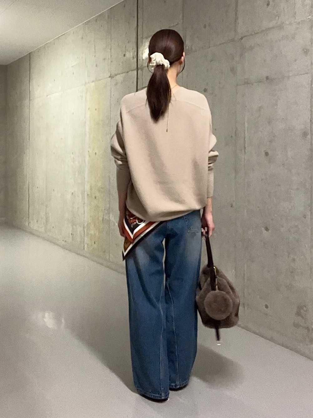 ブルー系のデニムパンツ、ブラウン系のハンドバッグ、ブラウン系のその他シューズを着用したレディースの秋コーディネートの3枚目の写真