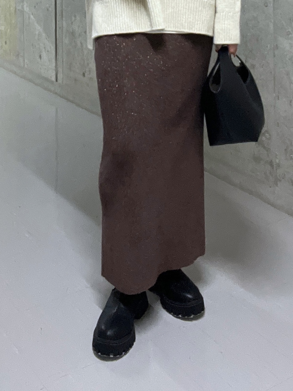 ホワイト系のニット/セーター、ブラウン系のスカート、ブラック系のブーツを着用したレディースの秋コーディネートの7枚目の写真