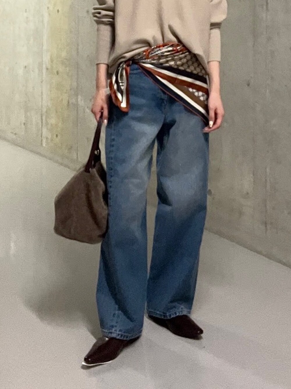 ブルー系のデニムパンツ、ブラウン系のハンドバッグ、ブラウン系のその他シューズを着用したレディースの秋コーディネートの7枚目の写真