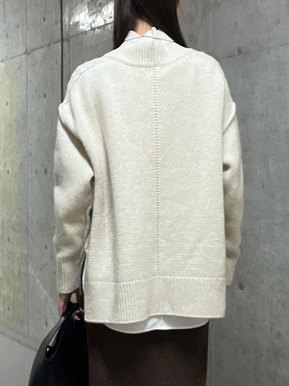 ホワイト系のニット/セーター、ブラウン系のスカート、ブラック系のブーツを着用したレディースの秋コーディネートの6枚目の写真