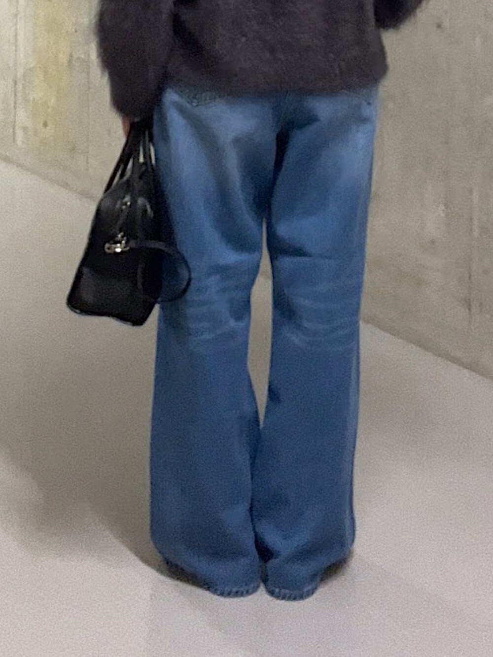 グレー系のニット/セーター、ホワイト系のシャツ/ブラウス、ブルー系のデニムパンツを着用したレディースの秋コーディネートの9枚目の写真