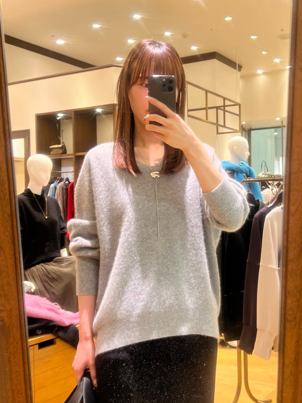 グレー系のニット/セーター、ブラック系のスカート、ブラック系のブーツを着用したレディースの冬コーディネートの2枚目の写真