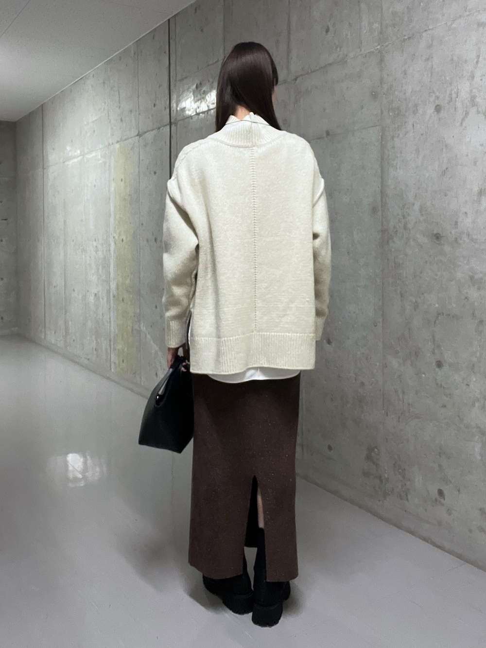 ホワイト系のニット/セーター、ブラウン系のスカート、ブラック系のブーツを着用したレディースの秋コーディネートの3枚目の写真