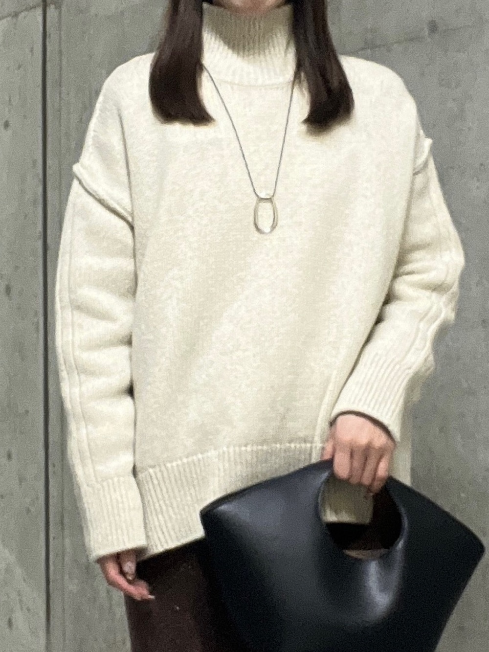 ホワイト系のニット/セーター、ブラウン系のスカート、ブラック系のブーツを着用したレディースの秋コーディネートの4枚目の写真