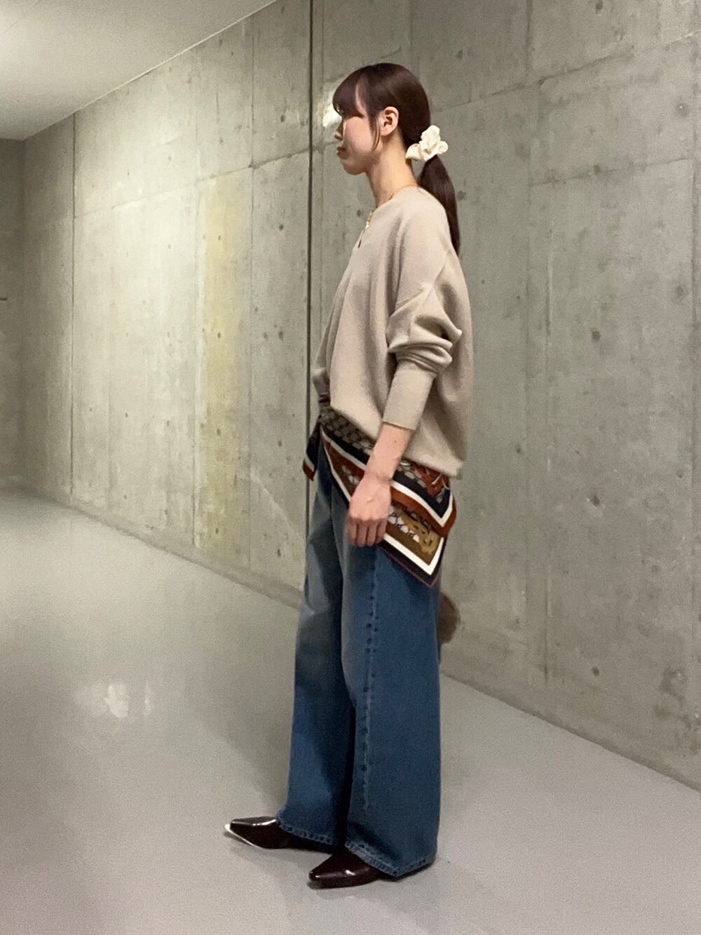 ブルー系のデニムパンツ、ブラウン系のハンドバッグ、ブラウン系のその他シューズを着用したレディースの秋コーディネートの2枚目の写真