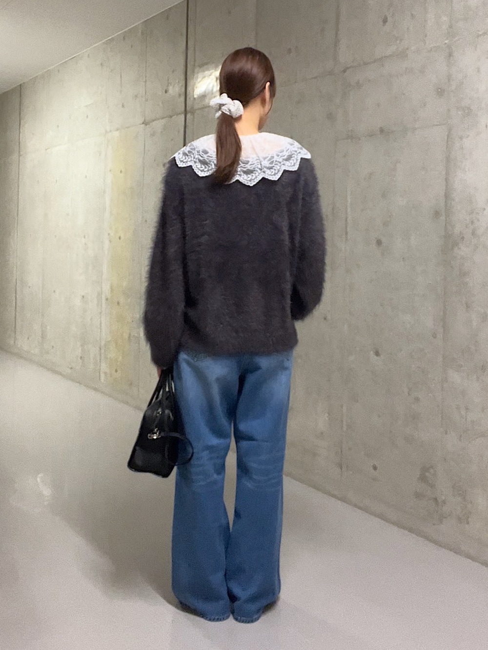 グレー系のニット/セーター、ホワイト系のシャツ/ブラウス、ブルー系のデニムパンツを着用したレディースの秋コーディネートの3枚目の写真