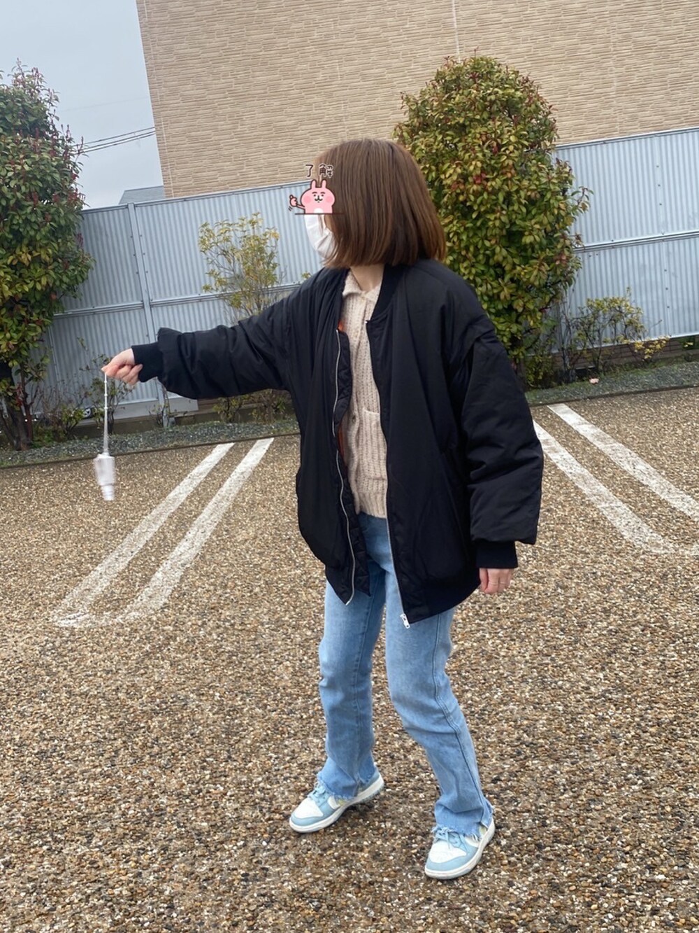 ブルー系のデニムパンツ、ベージュ系のカーディガン/ボレロ、ブラック系のミリタリージャケットを着用したレディースの春コーディネートの2枚目の写真