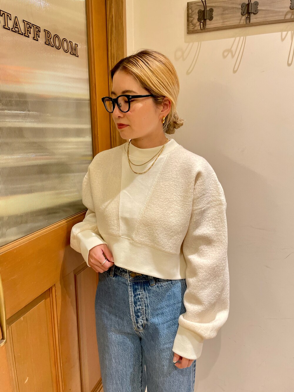 ブラウン系のステンカラーコート、ホワイト系のスウェット、ブルー系のデニムパンツを着用したレディースの秋コーディネートの3枚目の写真