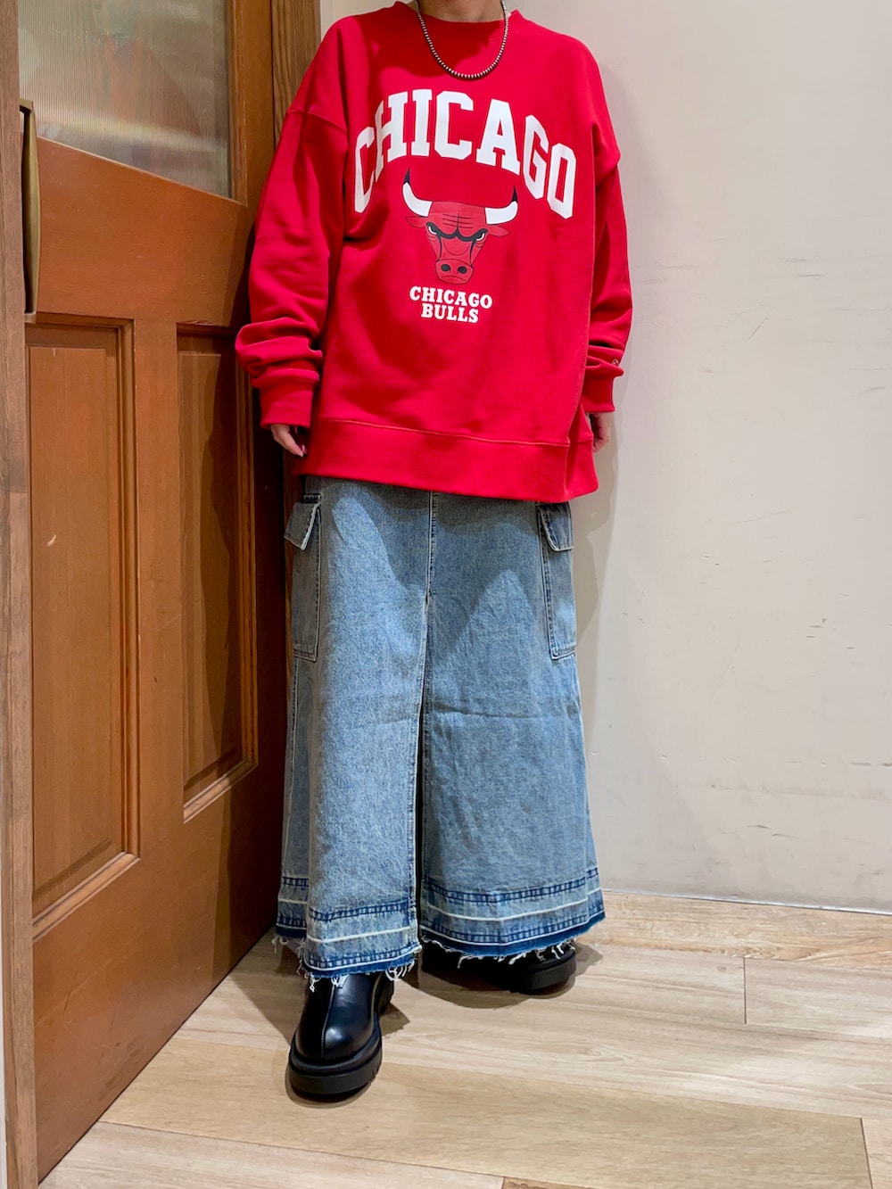 レッド系のスウェット、ブルー系のスカート、ブラック系のハンドバッグを着用したレディースの秋コーディネートの5枚目の写真