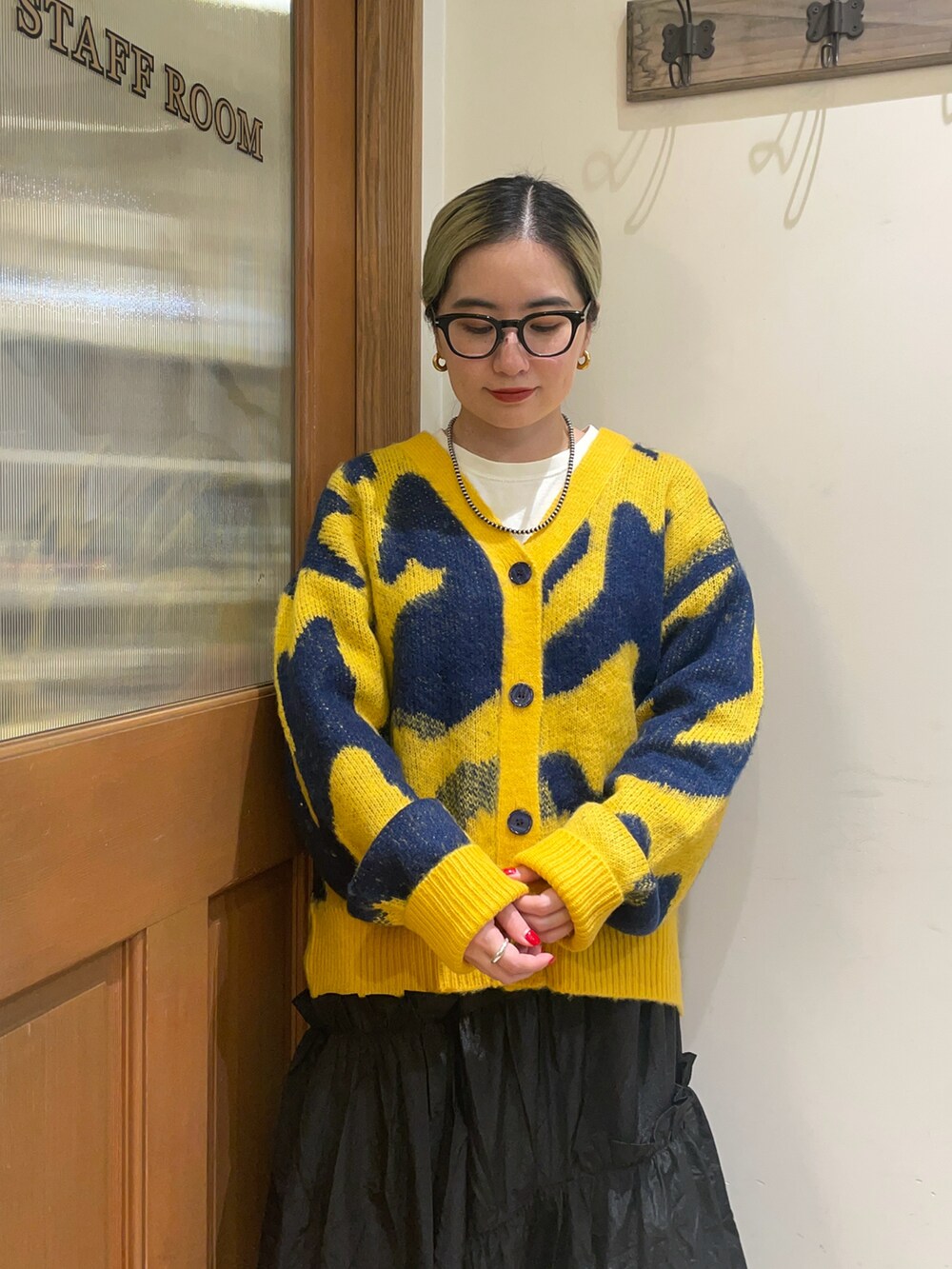 イエロー系のカーディガン/ボレロ、ブラック系のスカート、シルバー系のブーツを着用したレディースの冬コーディネートの3枚目の写真