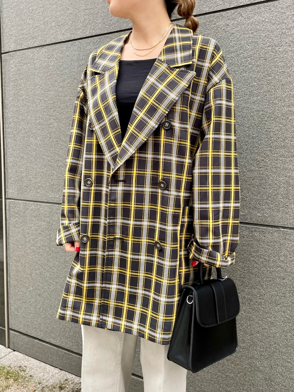 ブラック系のテーラードジャケット、ブラック系のハンドバッグ、グレー系のデニムパンツを着用したレディースの春コーディネートの2枚目の写真