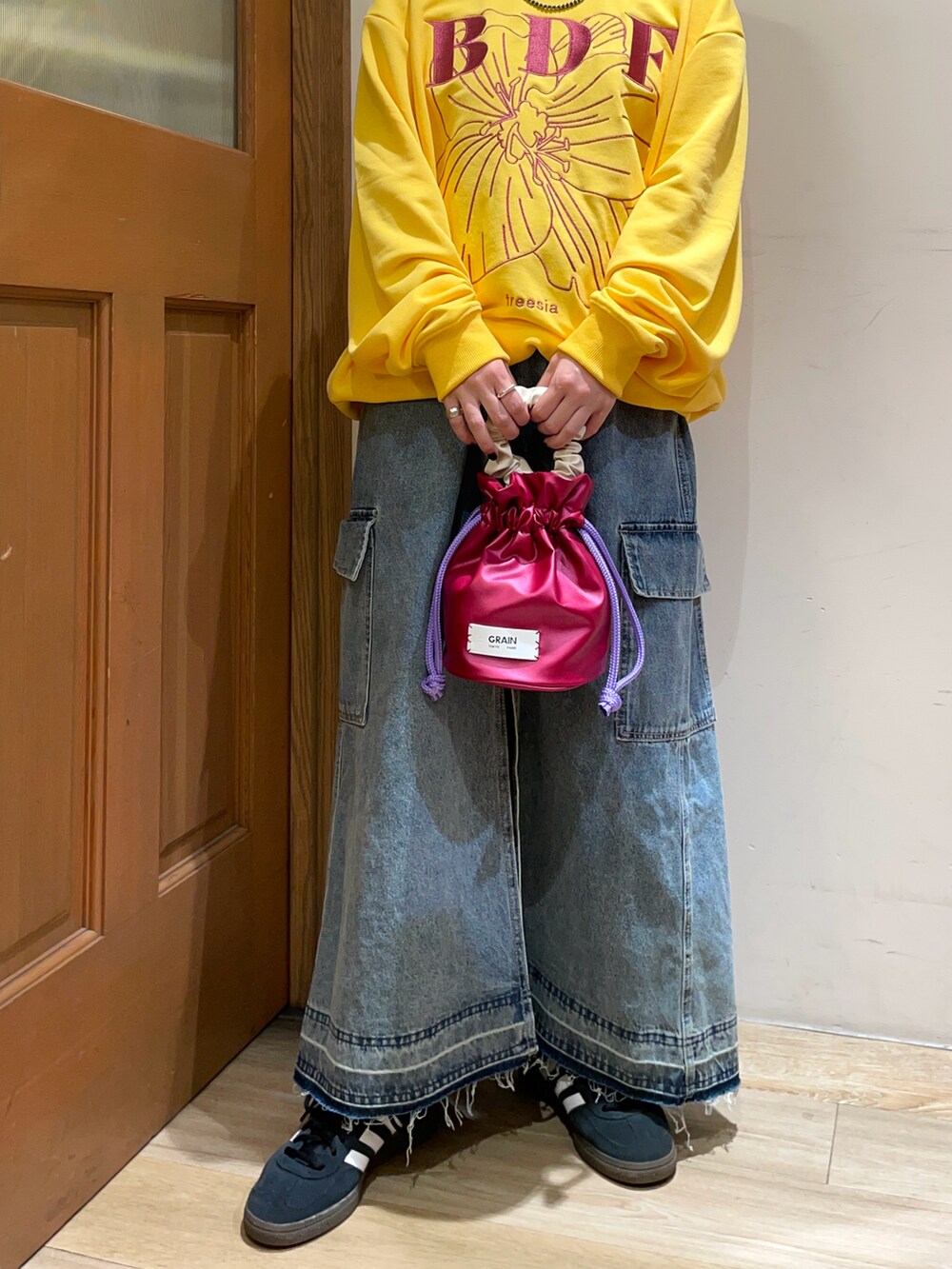 イエロー系のスウェット、ブルー系のスカート、ブラック系のハンドバッグを着用したレディースの秋コーディネートの5枚目の写真