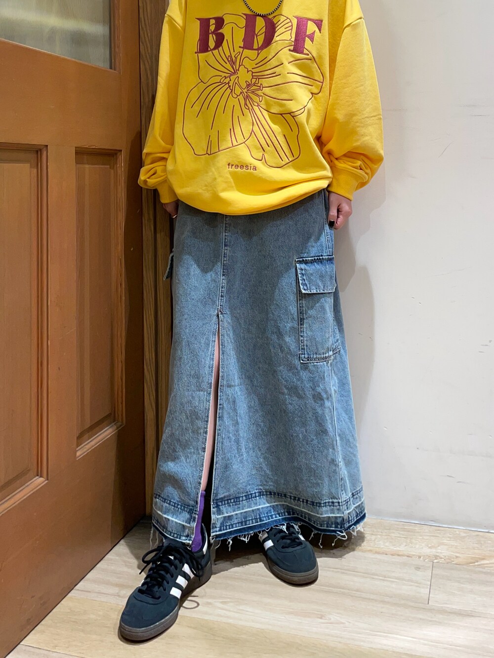 イエロー系のスウェット、ブルー系のスカート、ブラック系のハンドバッグを着用したレディースの秋コーディネートの4枚目の写真