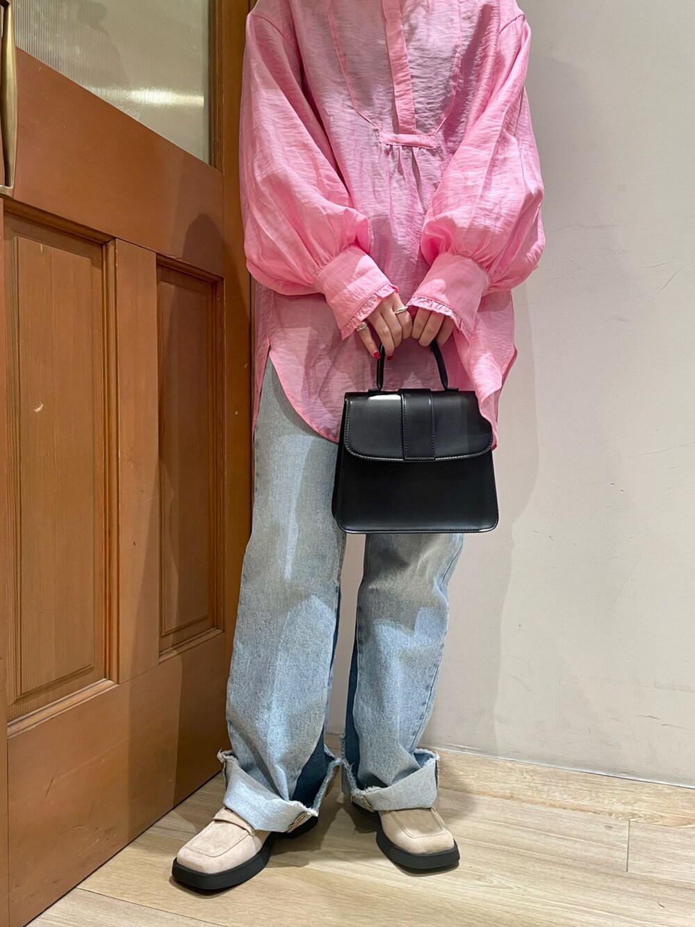 ピンク系のシャツ/ブラウス、ブラック系のハンドバッグ、ブルー系のデニムパンツを着用したレディースの春コーディネートの4枚目の写真