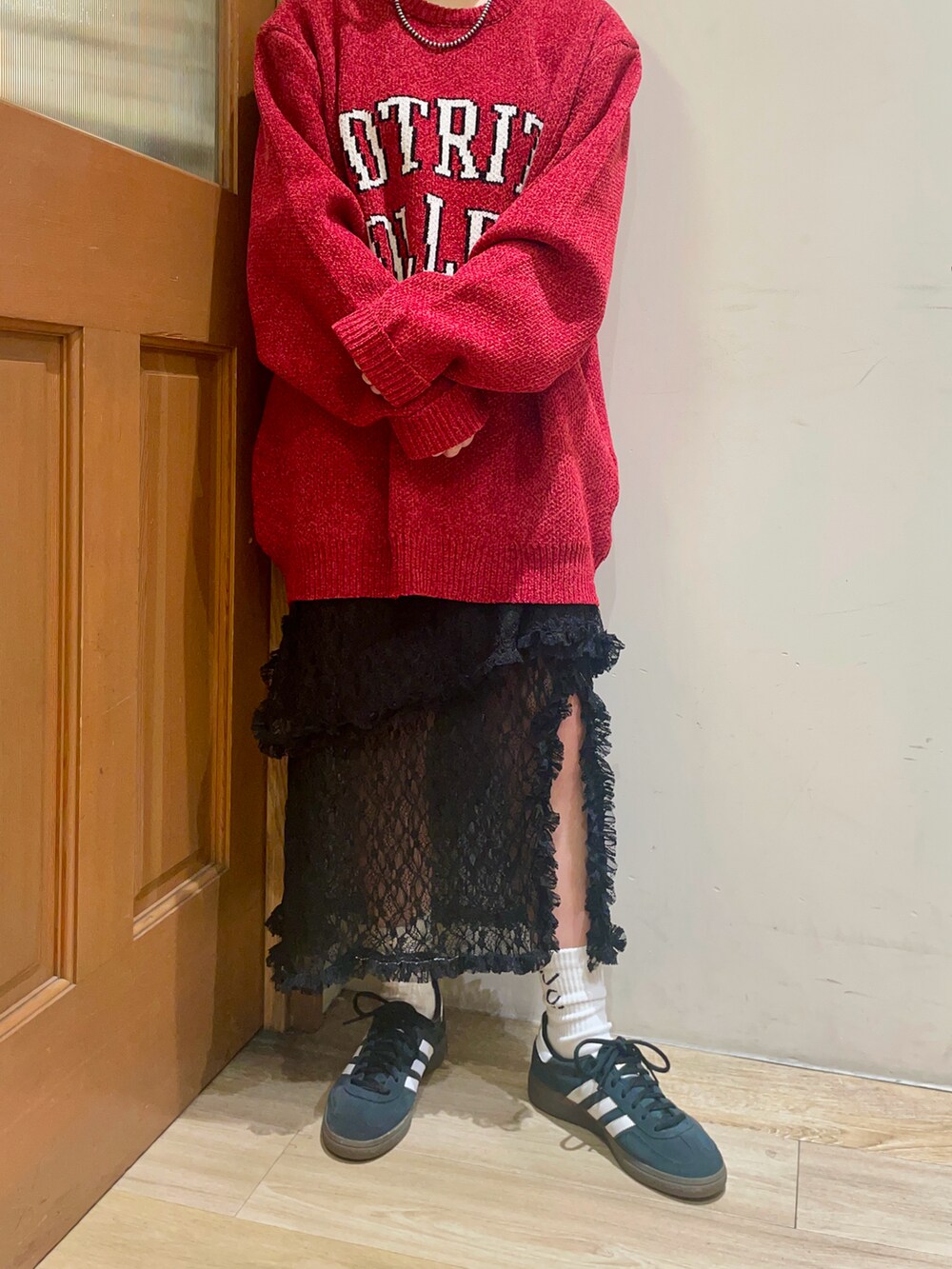 レッド系のニット/セーター、ブラック系のスカート、ブラウン系のハンドバッグを着用したレディースの秋コーディネートの5枚目の写真