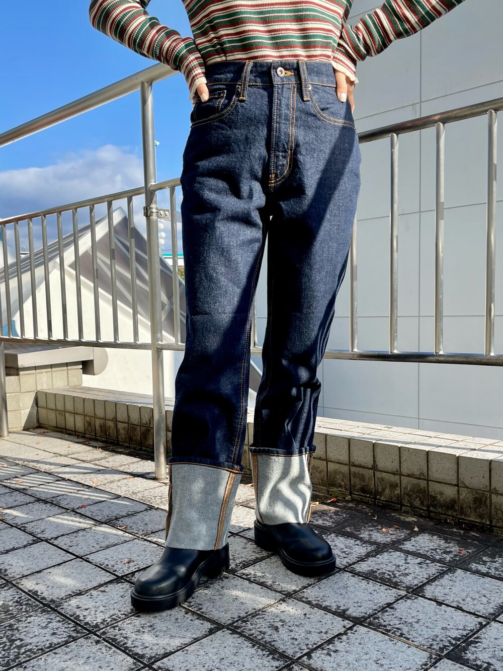 グリーン系のニット/セーター、ブルー系のデニムパンツ、ブラック系のブーツを着用したレディースの秋コーディネートの4枚目の写真