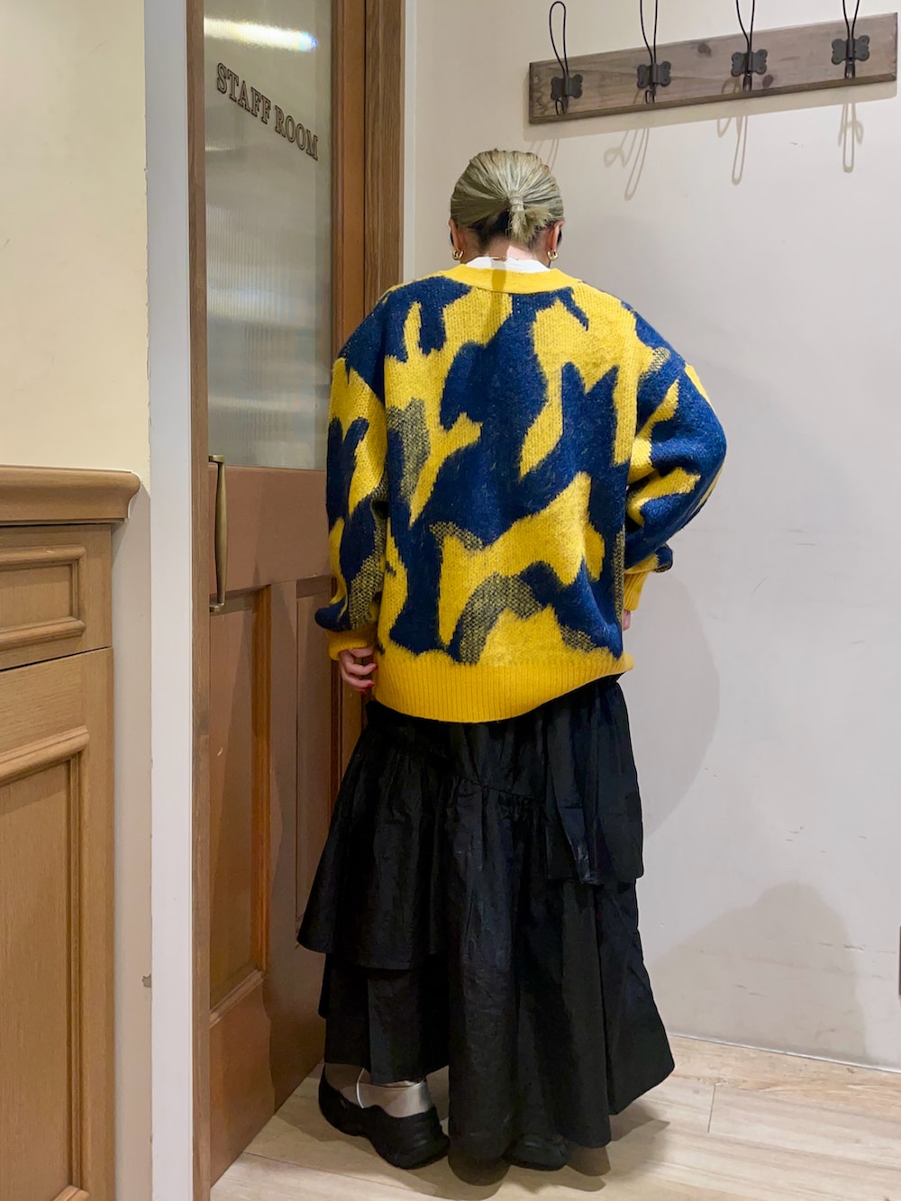 イエロー系のカーディガン/ボレロ、ブラック系のスカート、シルバー系のブーツを着用したレディースの冬コーディネートの2枚目の写真