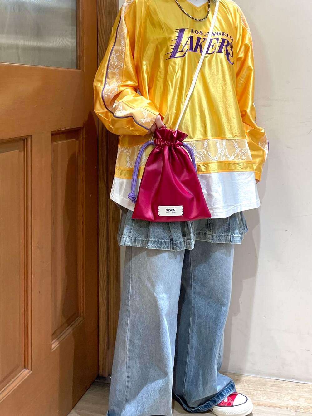 イエロー系のTシャツ/カットソー、ブラウン系のショルダーバッグ、ブルー系のデニムパンツを着用したレディースの秋コーディネートの5枚目の写真