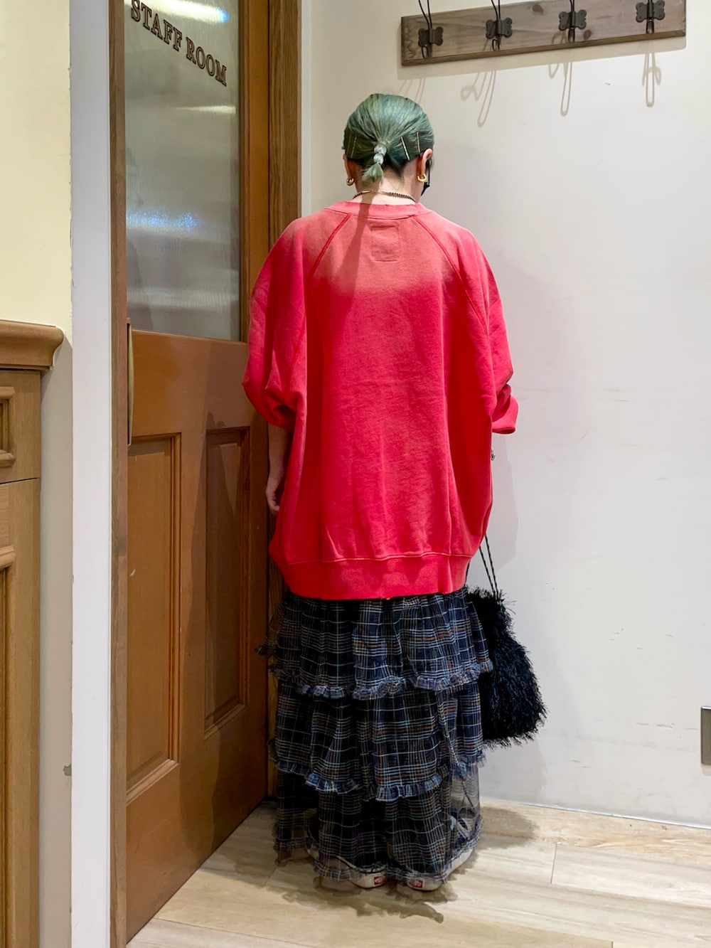 レッド系のトップス、ブラック系のスカートを着用したレディースの秋コーディネートの2枚目の写真