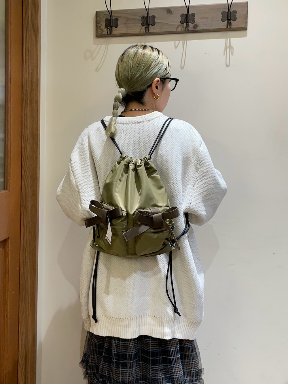 ホワイト系のニット/セーター、グリーン系のバックパック/リュック、ブラック系のスカートを着用したレディースの秋コーディネートの5枚目の写真