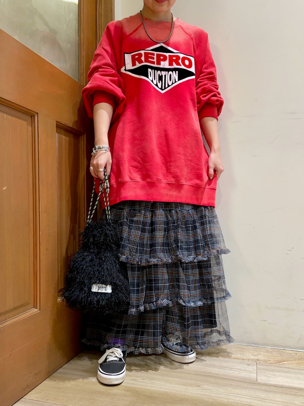 レッド系のトップス、ブラック系のスカートを着用したレディースの秋コーディネートの5枚目の写真