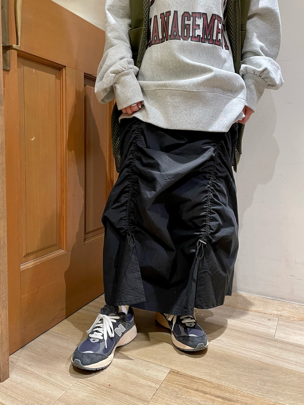 グレー系のスウェット、グリーン系のベスト、ブラック系のスカートを着用したレディースの秋コーディネートの5枚目の写真