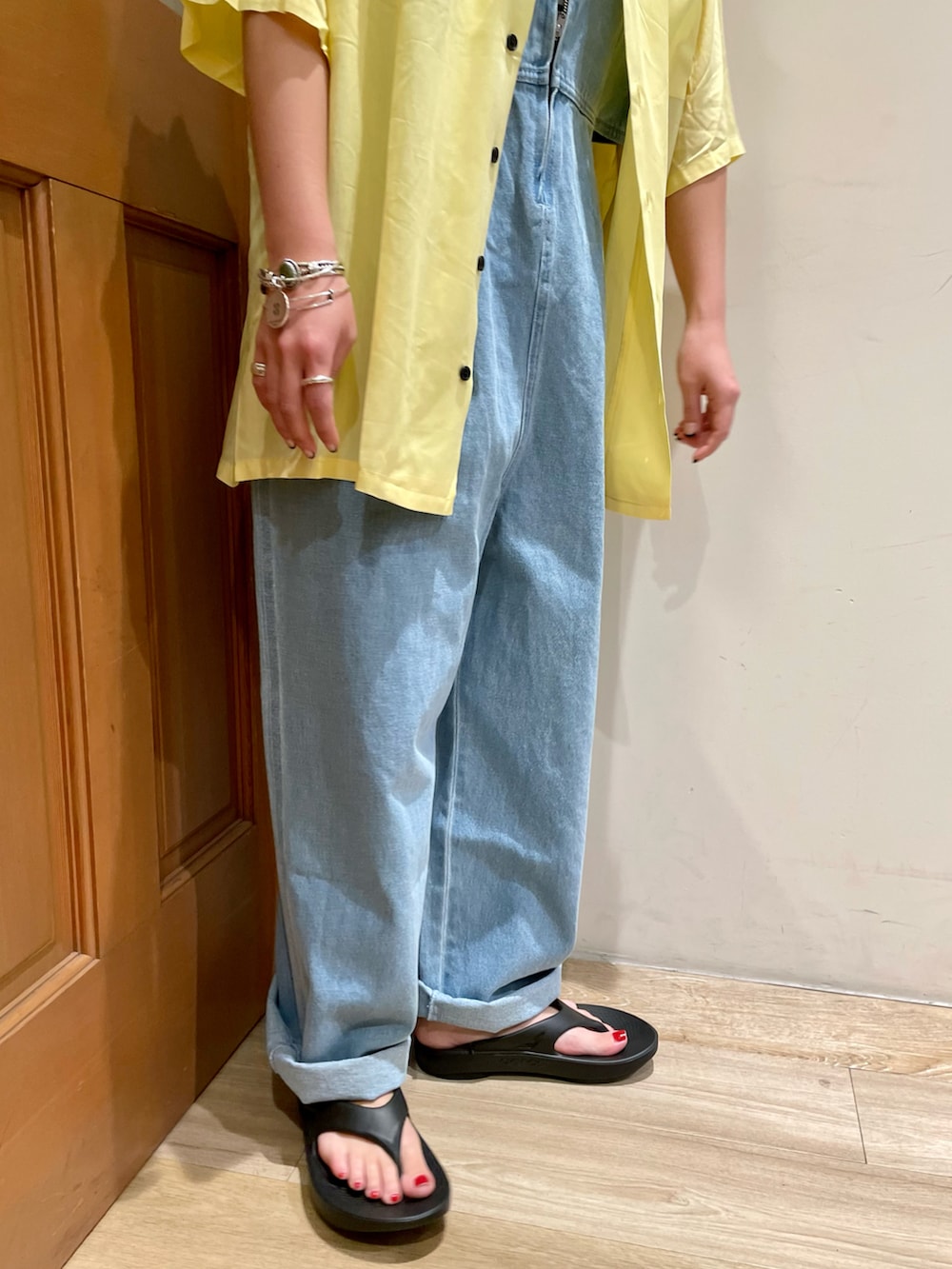 ブルー系のサロペット/オーバーオール、ブラック系のサンダル、イエロー系のシャツ/ブラウスを着用したレディースの夏コーディネートの4枚目の写真