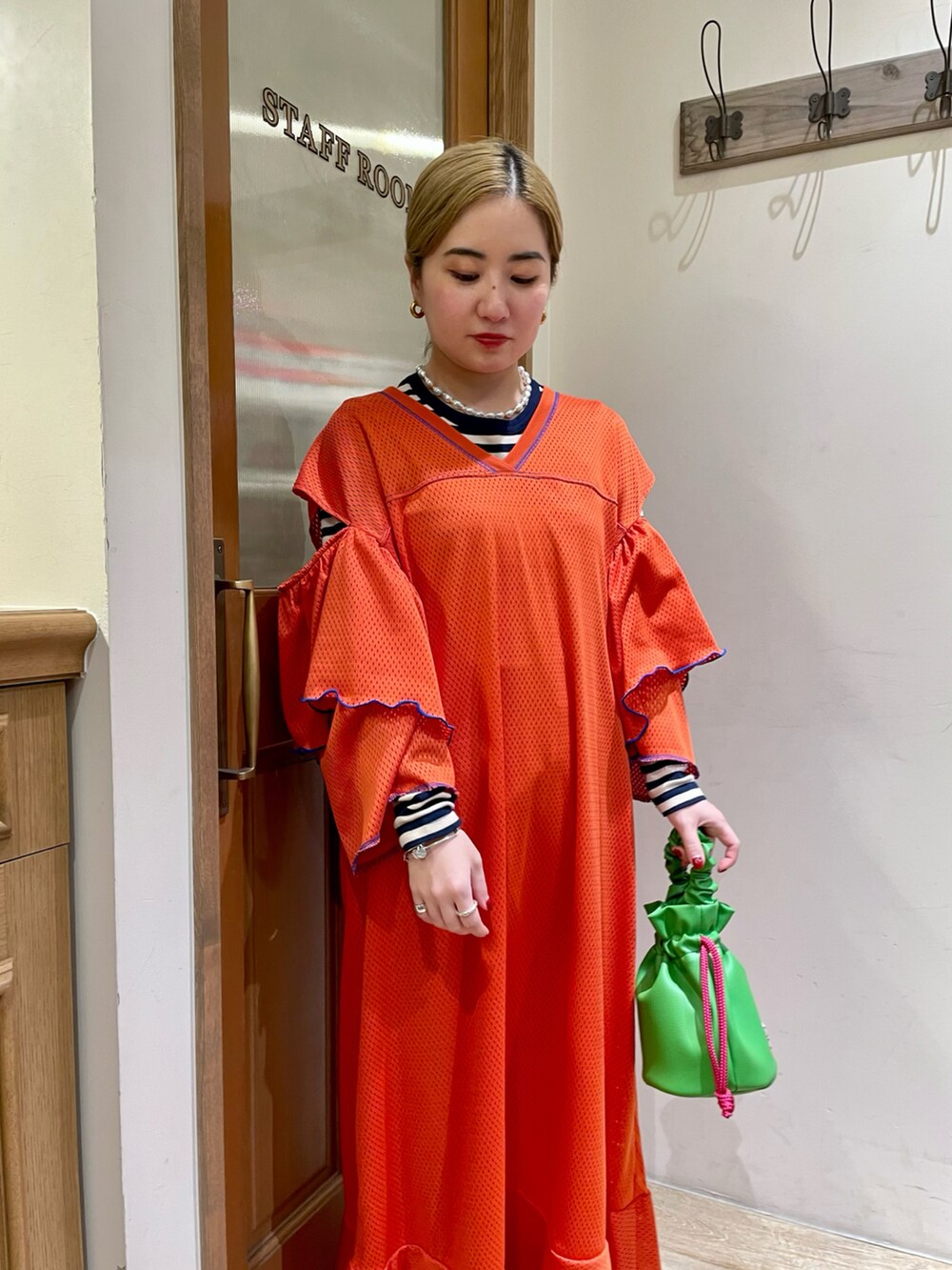 オレンジ系のワンピース/ドレス、ブラック系のハンドバッグ、ブルー系のデニムパンツを着用したレディースの秋コーディネートの3枚目の写真