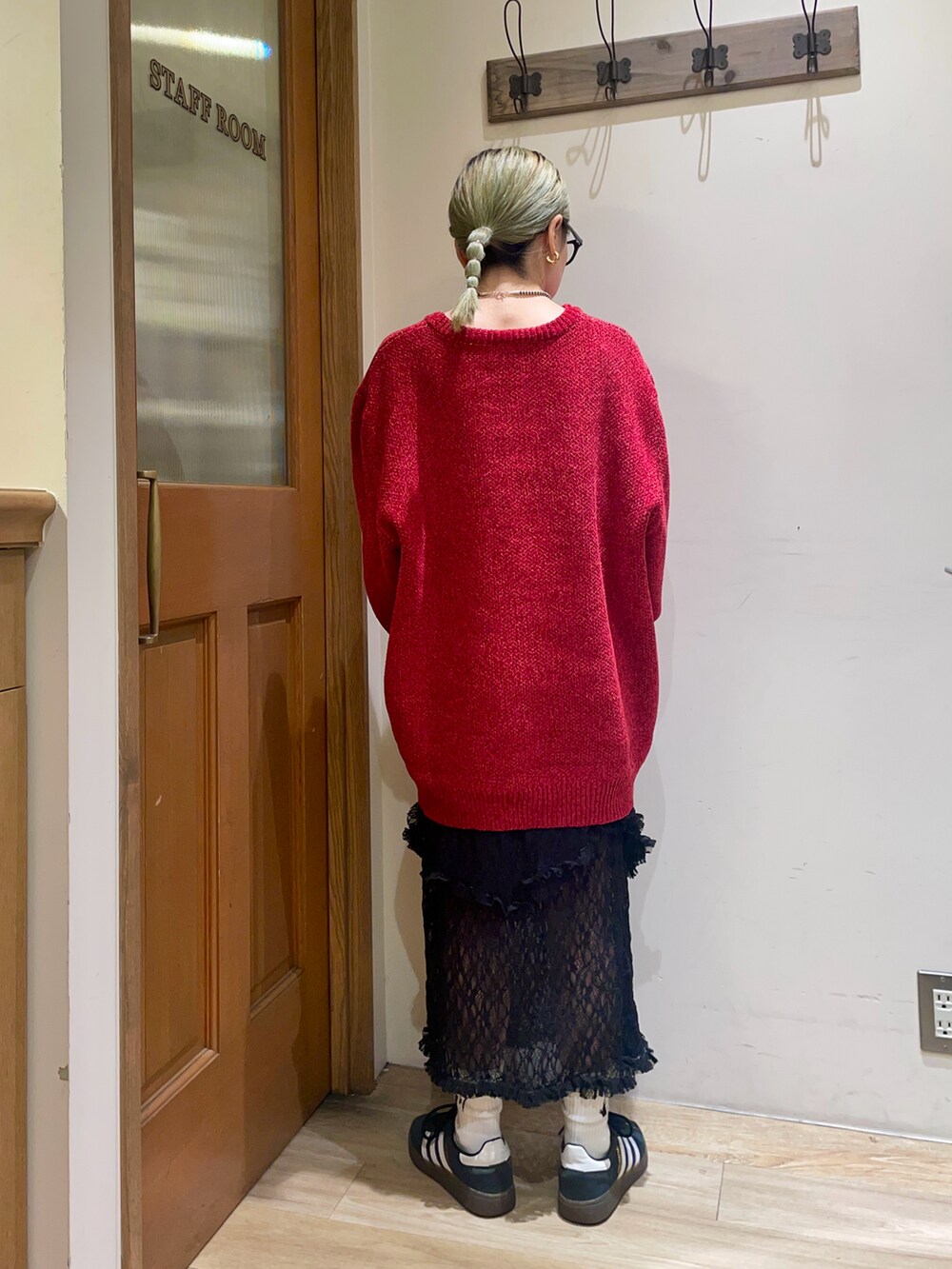 レッド系のニット/セーター、ブラック系のスカート、ブラウン系のハンドバッグを着用したレディースの秋コーディネートの2枚目の写真