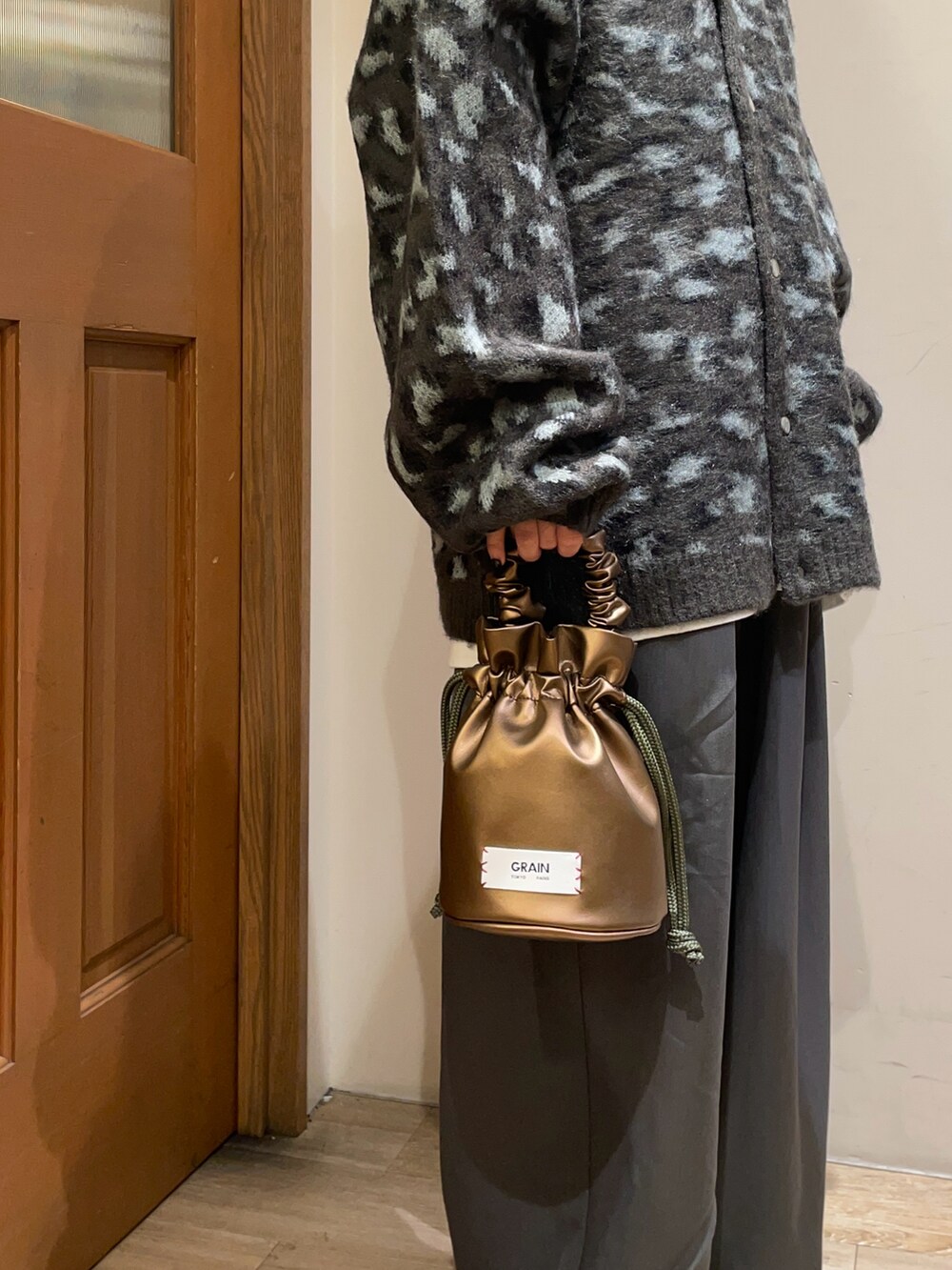 ベージュ系のカーディガン/ボレロ、グレー系のスラックス、ブラック系のハンドバッグを着用したレディースの秋コーディネートの5枚目の写真