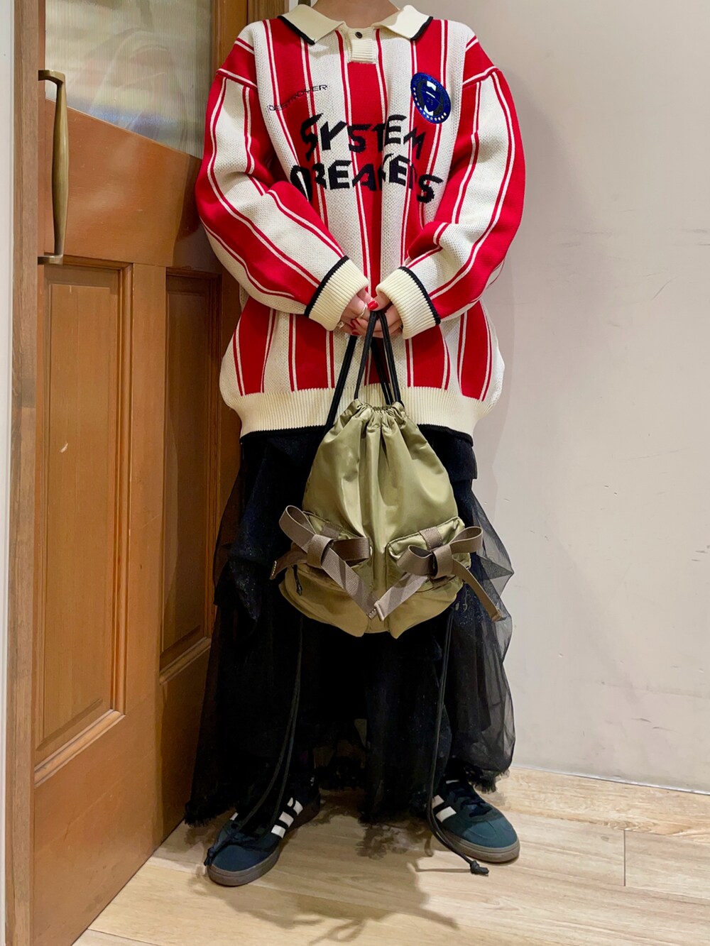 グリーン系のバックパック/リュック、ブラック系のスカート、レッド系のニット/セーターを着用したレディースの秋コーディネートの5枚目の写真