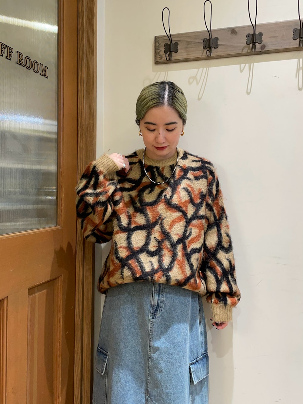 ブラウン系のニット/セーター、ブラック系のハンドバッグ、ブルー系のスカートを着用したレディースの秋コーディネートの3枚目の写真