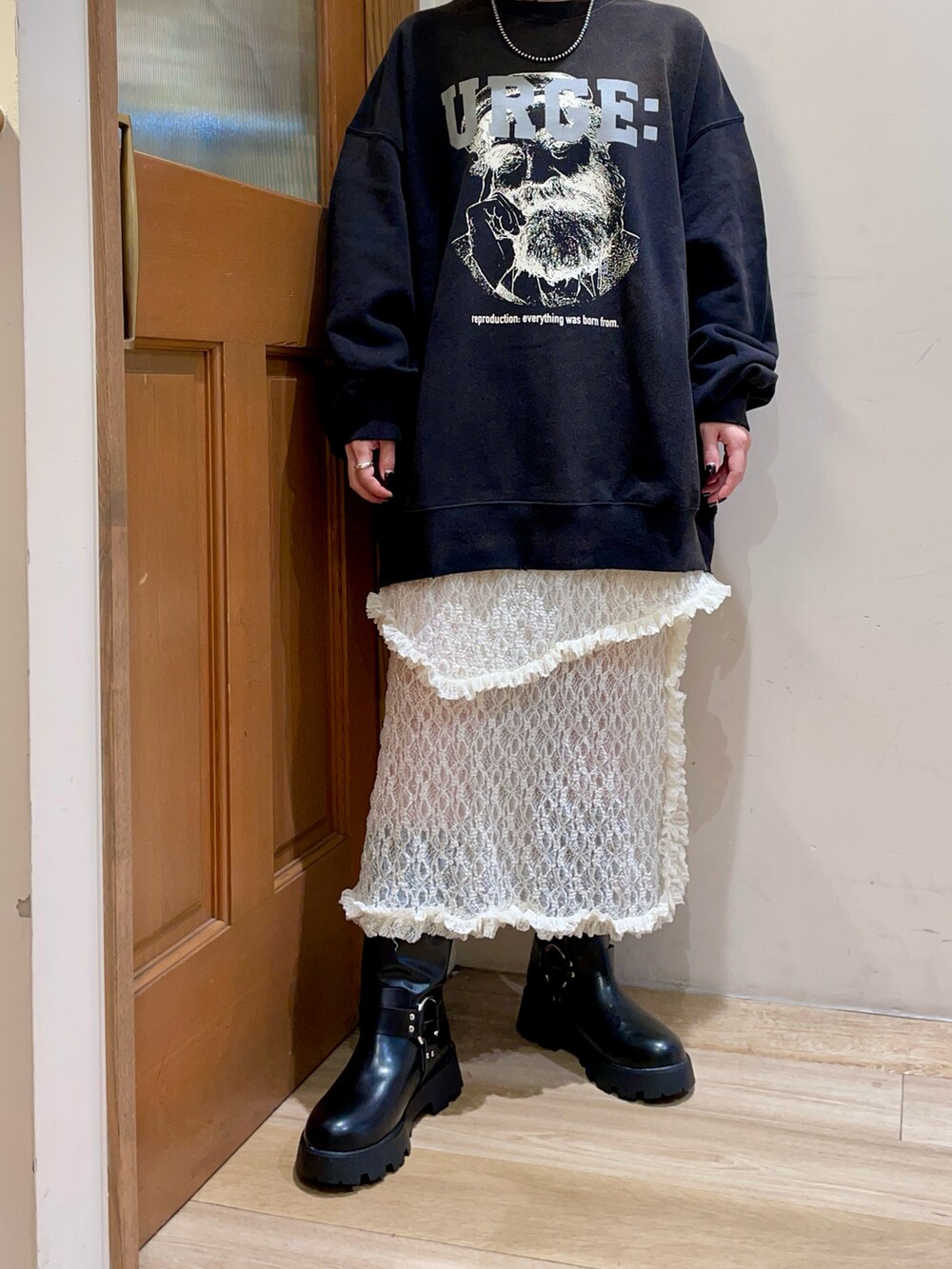 ブラック系のトップス、ホワイト系のスカート、ブラック系のブーツを着用したレディースの秋コーディネートの4枚目の写真