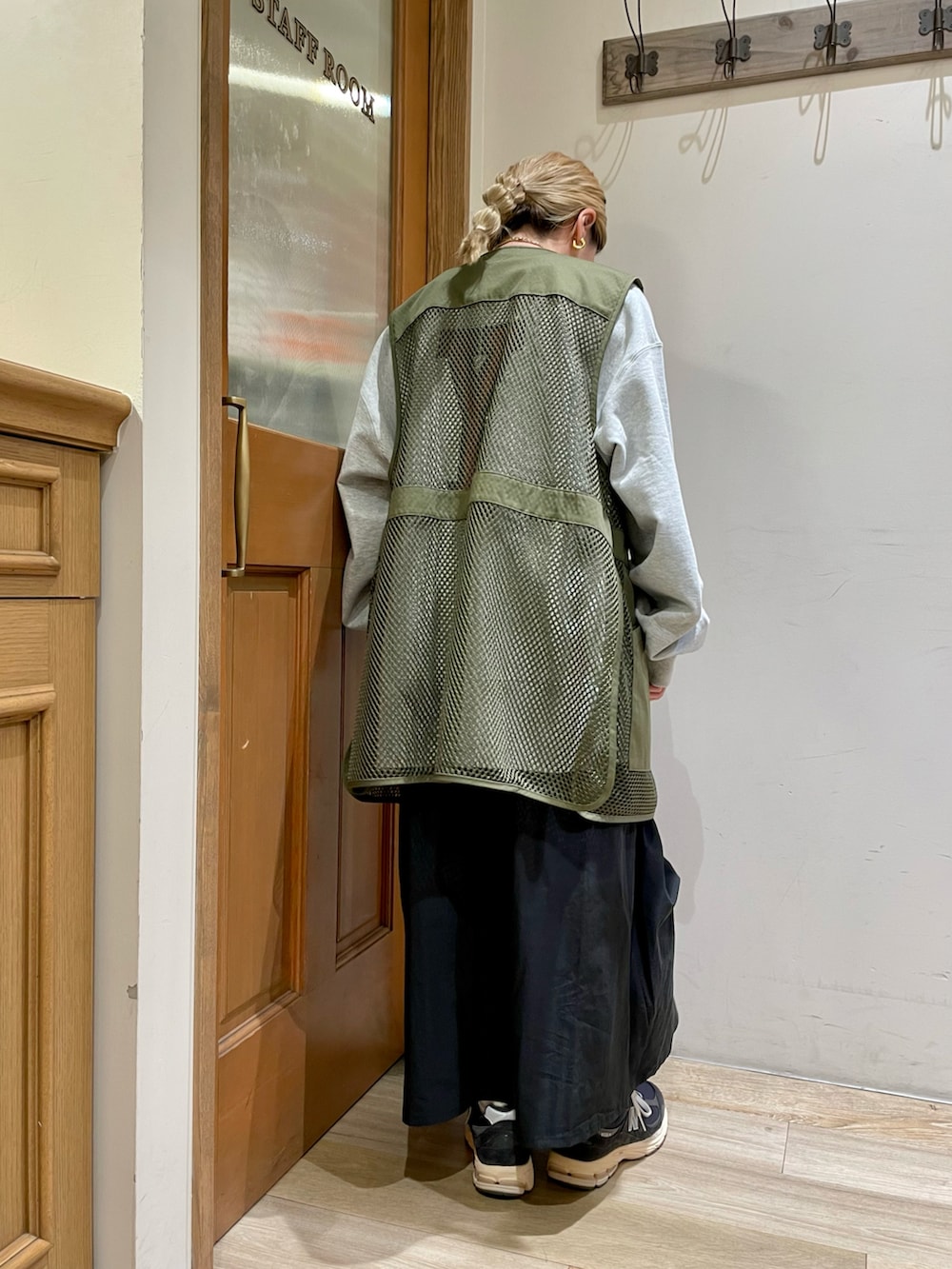 グレー系のスウェット、グリーン系のベスト、ブラック系のスカートを着用したレディースの秋コーディネートの2枚目の写真