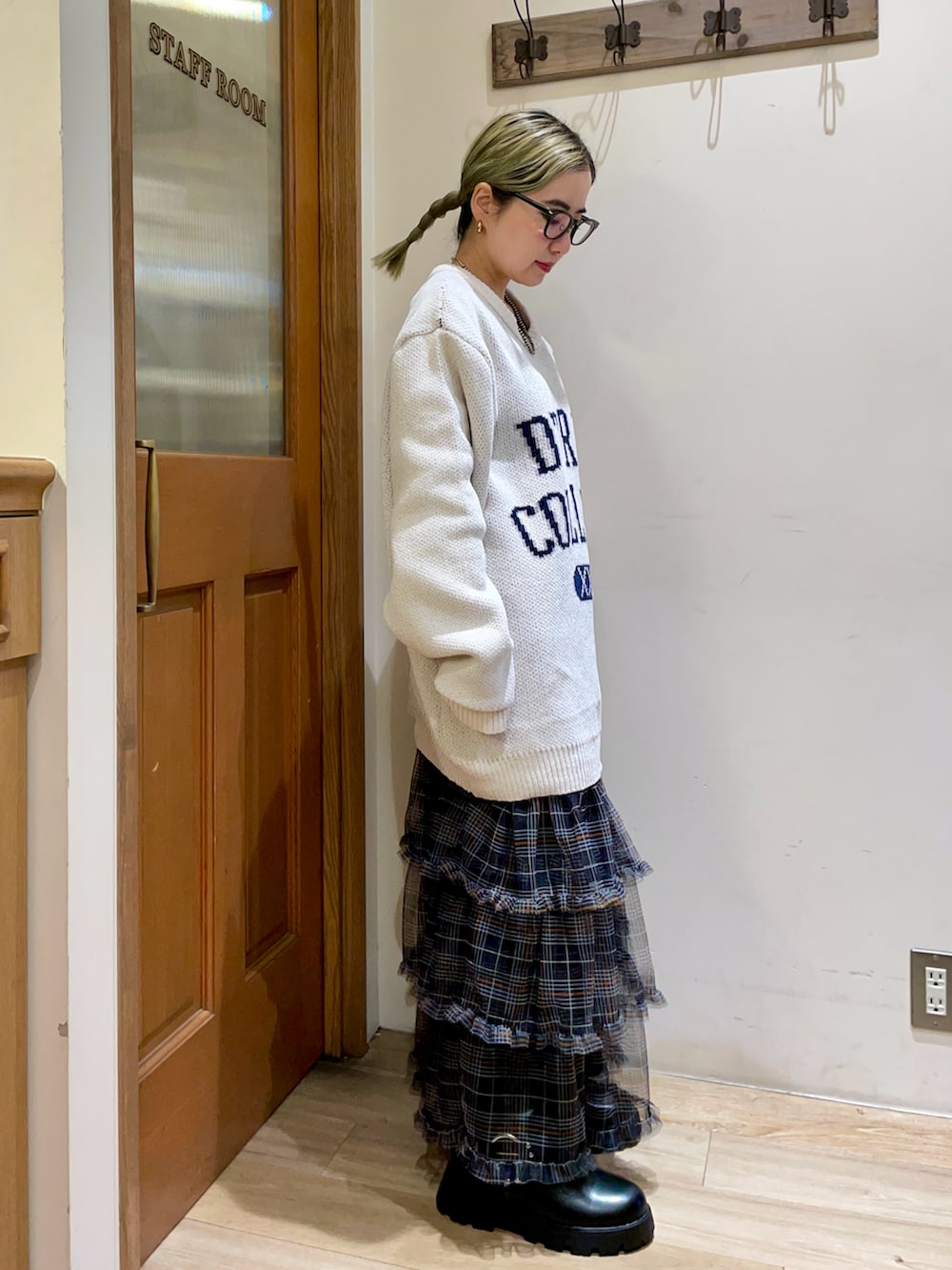 ホワイト系のニット/セーター、グリーン系のバックパック/リュック、ブラック系のスカートを着用したレディースの秋コーディネートの2枚目の写真