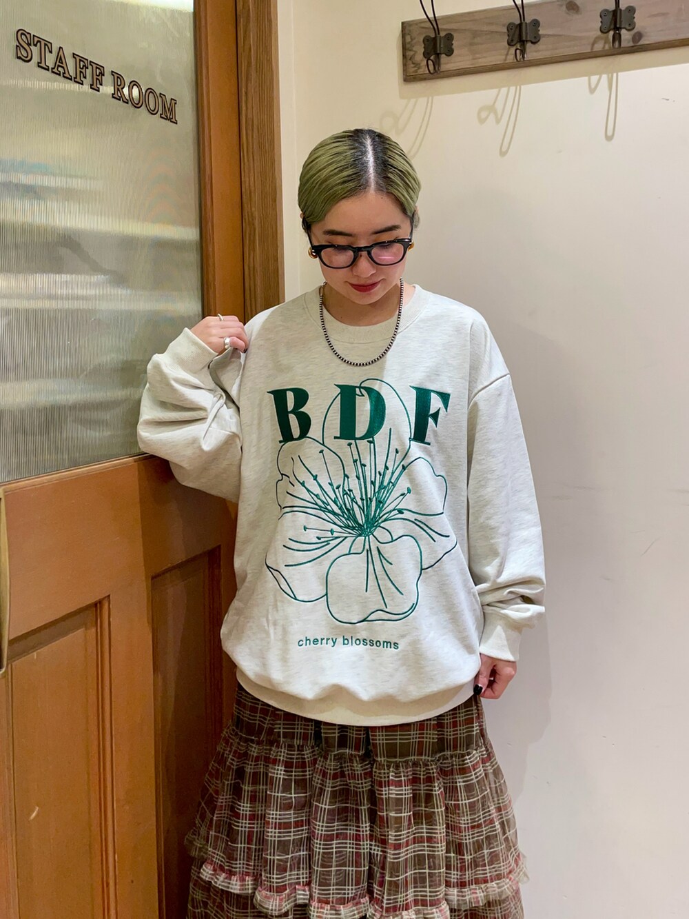 グレー系のスウェット、ブラウン系のスカート、ブルー系のデニムパンツを着用したレディースの秋コーディネートの3枚目の写真