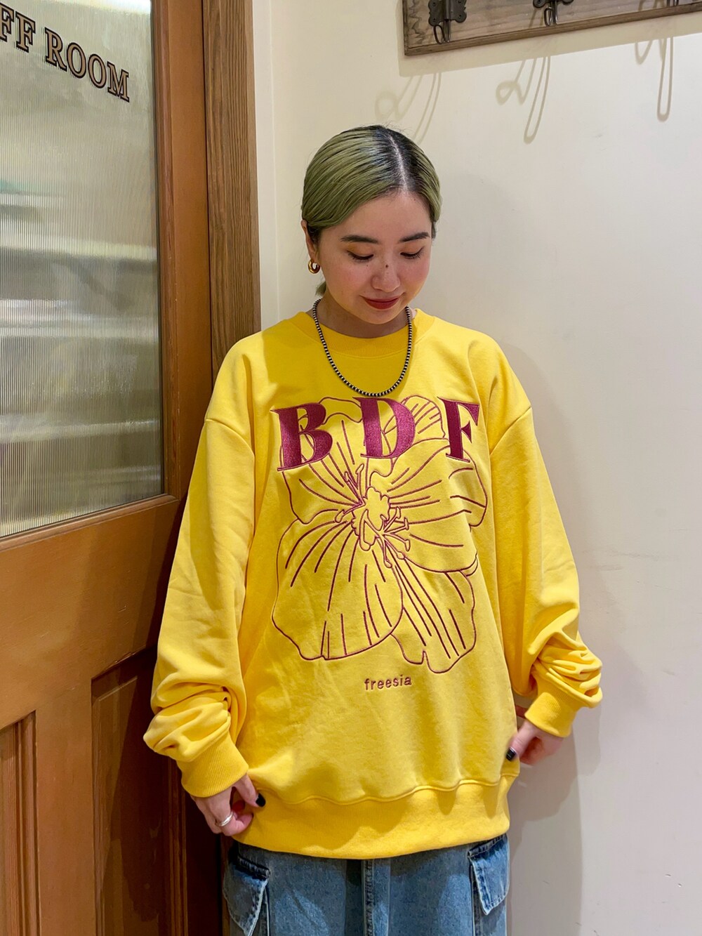 イエロー系のスウェット、ブルー系のスカート、ブラック系のハンドバッグを着用したレディースの秋コーディネートの3枚目の写真