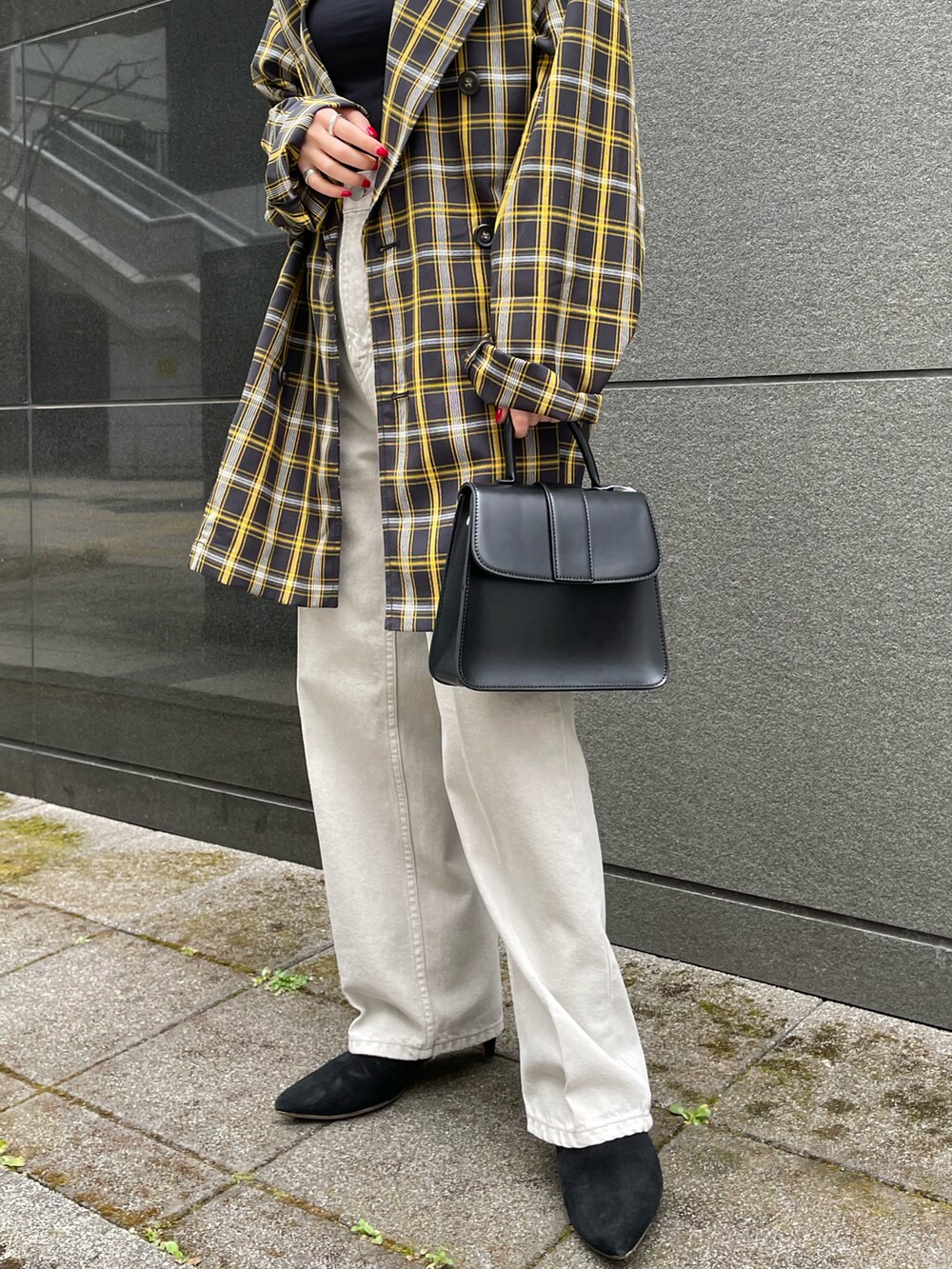 ブラック系のテーラードジャケット、ブラック系のハンドバッグ、グレー系のデニムパンツを着用したレディースの春コーディネートの5枚目の写真