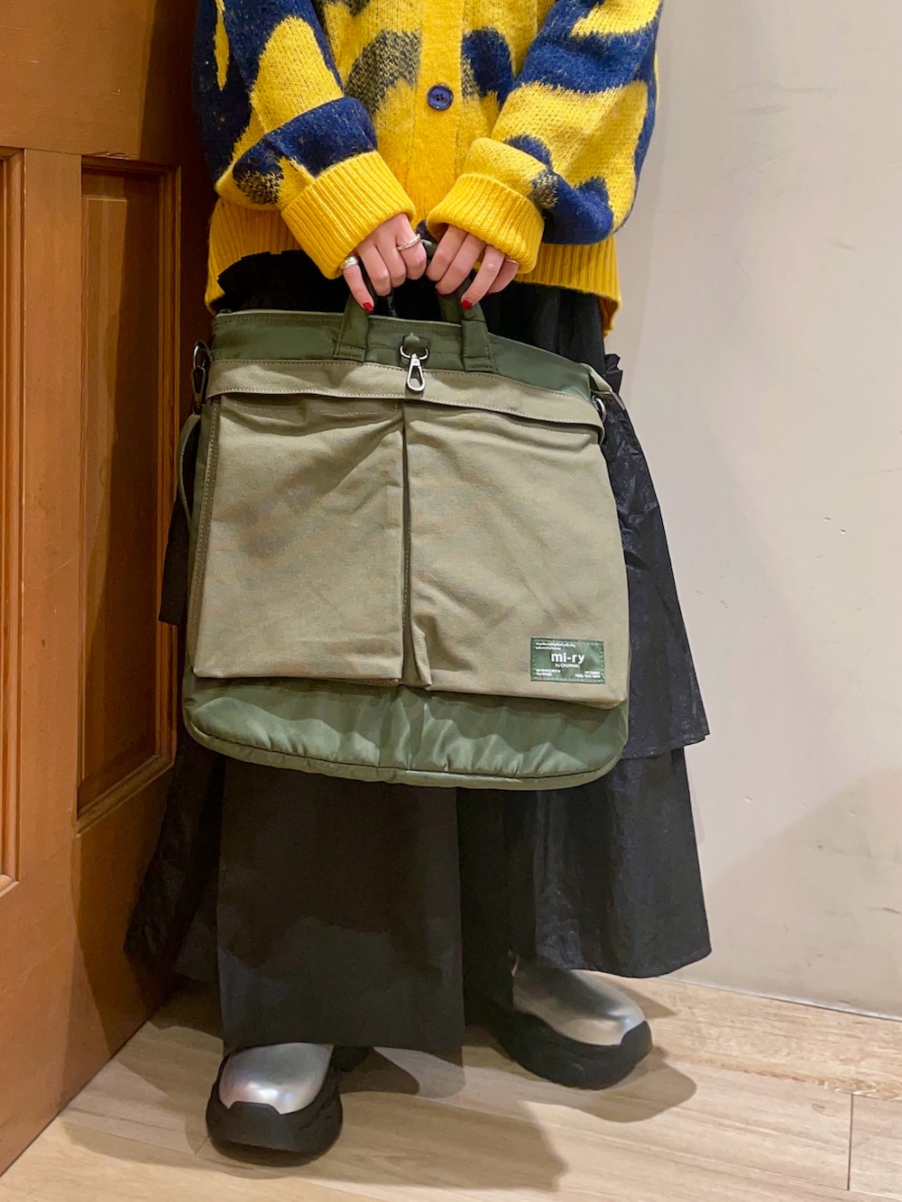 イエロー系のカーディガン/ボレロ、ブラック系のスカート、シルバー系のブーツを着用したレディースの冬コーディネートの5枚目の写真