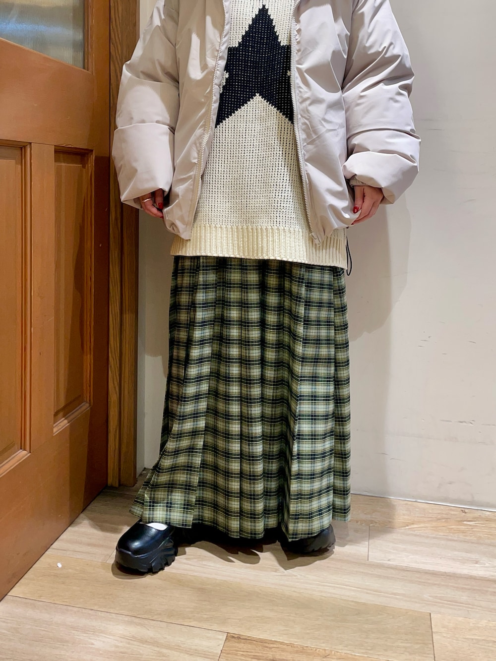 ホワイト系のニット/セーター、グレー系のダウンジャケット/コート、グリーン系のスカートを着用したレディースの冬コーディネートの4枚目の写真