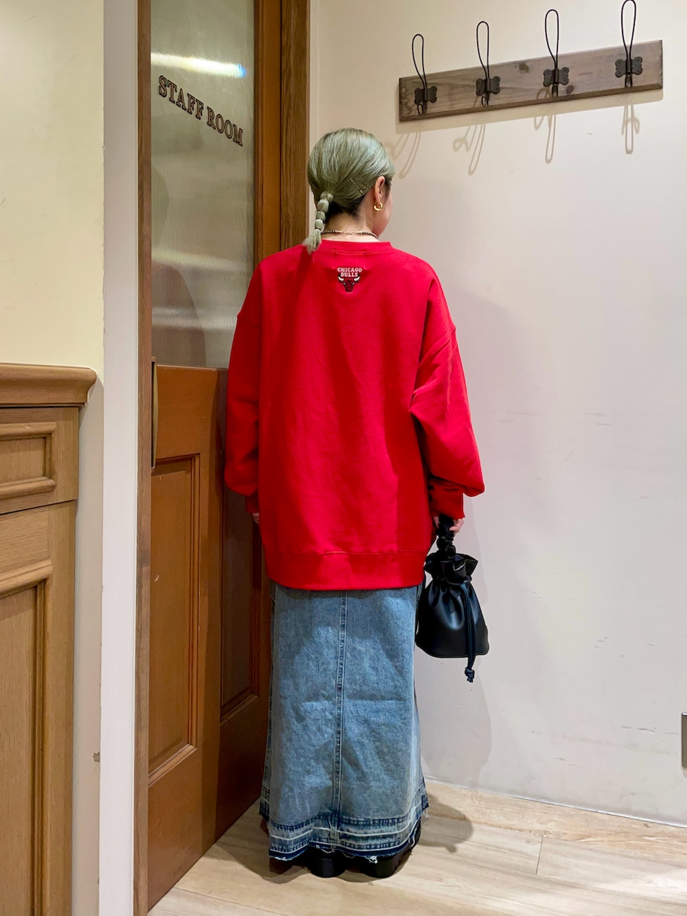 レッド系のスウェット、ブルー系のスカート、ブラック系のハンドバッグを着用したレディースの秋コーディネートの2枚目の写真