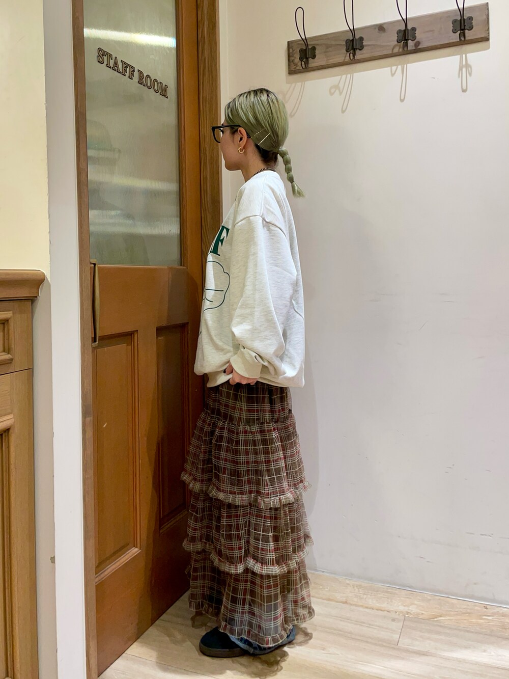 グレー系のスウェット、ブラウン系のスカート、ブルー系のデニムパンツを着用したレディースの秋コーディネートの2枚目の写真