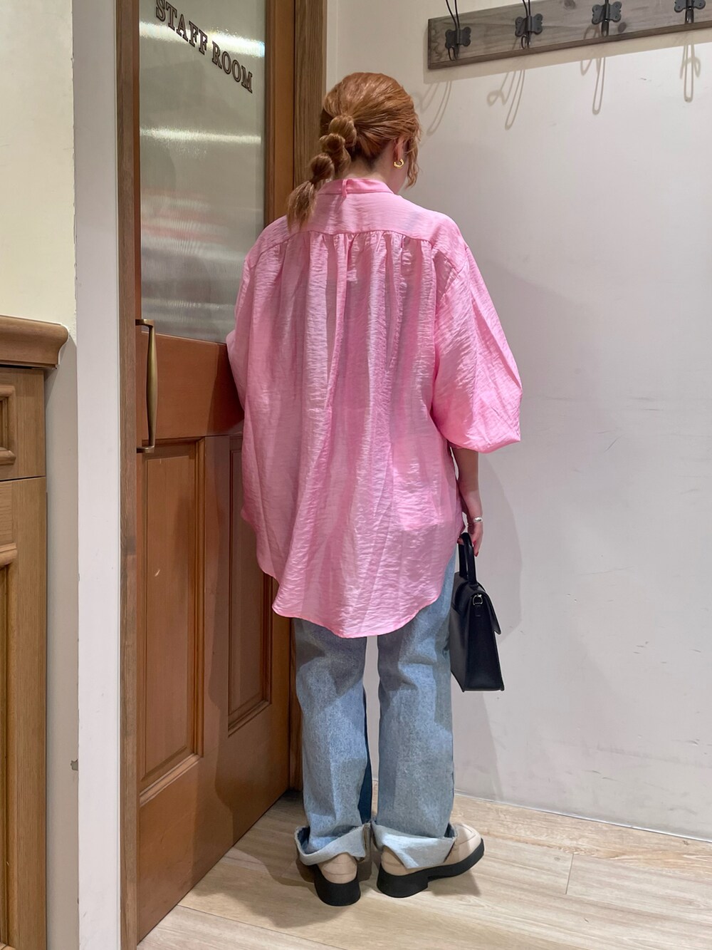 ピンク系のシャツ/ブラウス、ブラック系のハンドバッグ、ブルー系のデニムパンツを着用したレディースの春コーディネートの2枚目の写真