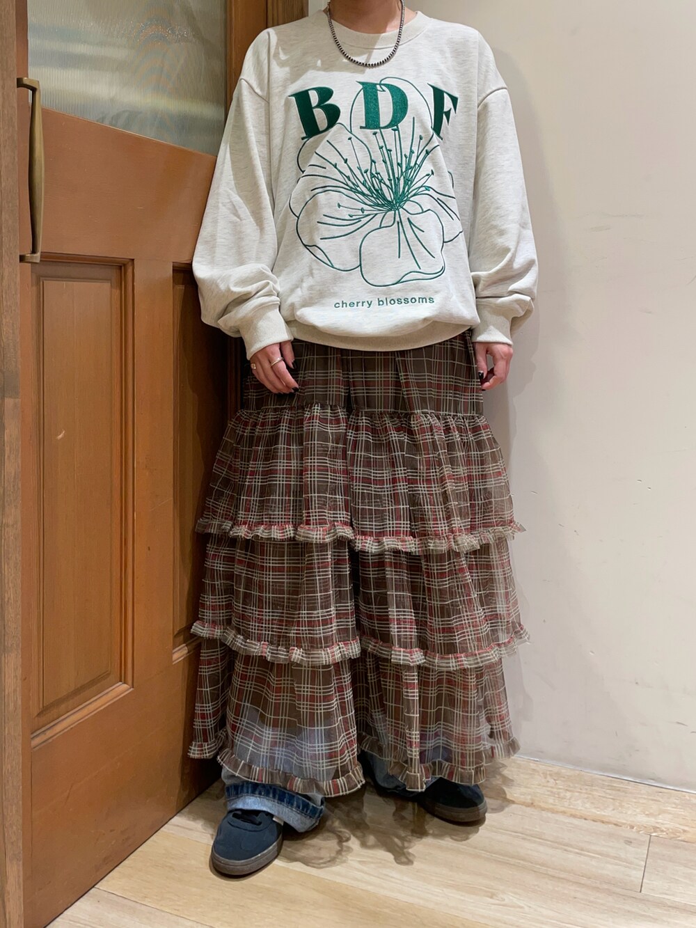 グレー系のスウェット、ブラウン系のスカート、ブルー系のデニムパンツを着用したレディースの秋コーディネートの4枚目の写真