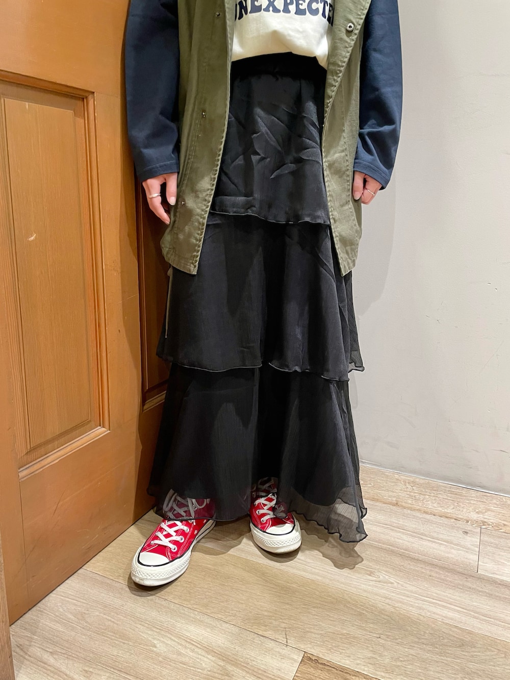 グリーン系のベスト、ブルー系のTシャツ/カットソー、ブラック系のスカートを着用したレディースの秋コーディネートの4枚目の写真